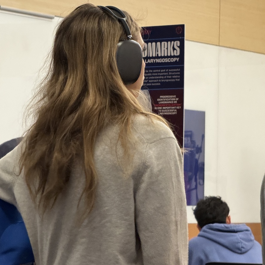 A learner studies a PACscape poster with headphones on.